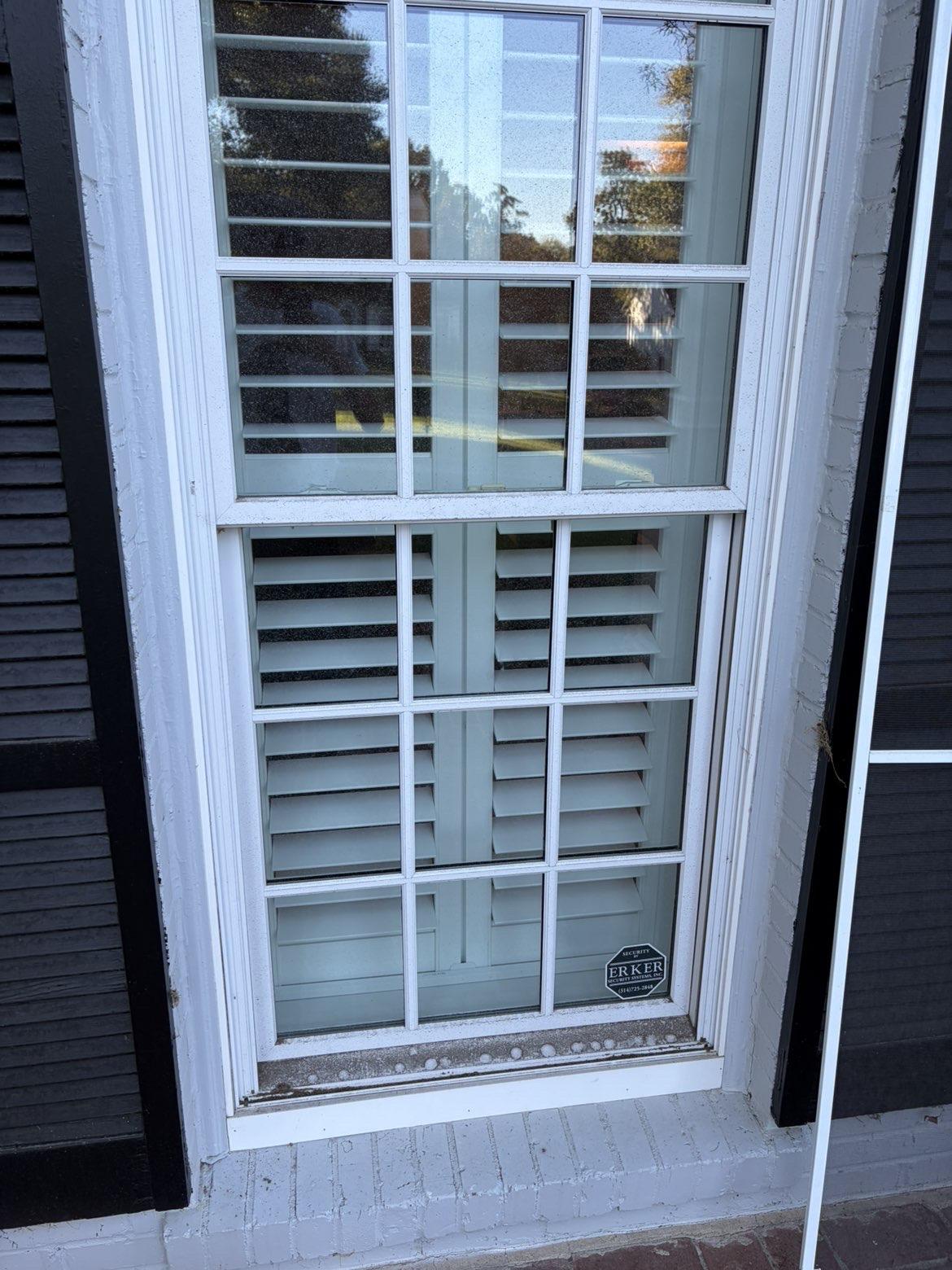 Before cleaning: White divided-light window beside dark shutters